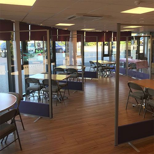 1800mm high morton full vision free standing office screens with clear acrylic and purple fabric. Positioned between tables at at cafe. 