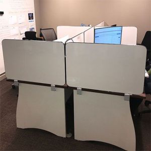 White gloss dry wipe desk divider panels connected to the back and sides of an office desk