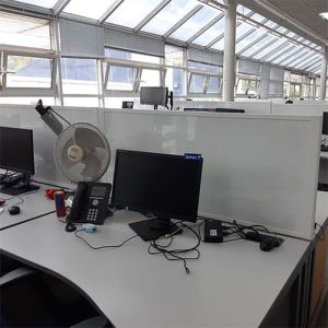 Easy clean, white gloss laminate desk divider attached to a desk in office setting